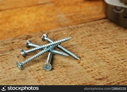 steel screws on wooden background.