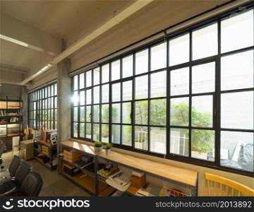 Steel windows in empty coworking space modern office room. Building facility desk and table. Business community center architecture interior and design area.