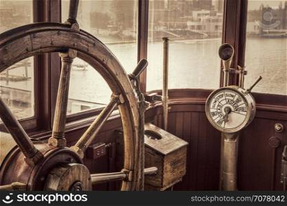 steering wheel and engine controls (telegraph) on a vintage ship bridge, retro sepia toning