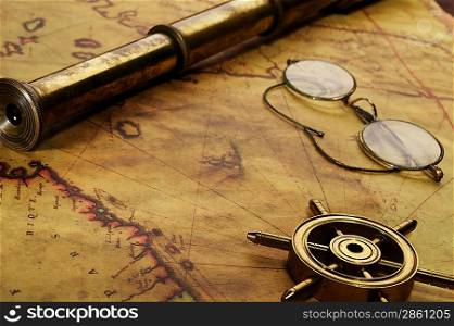 Steering wheel, glasses and spyglass on the old map