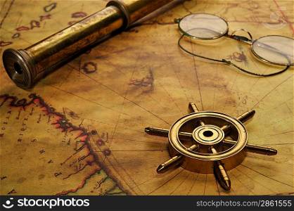 Steering wheel, glasses and spyglass on the old map