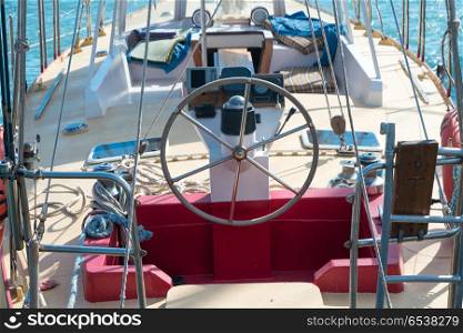 Steering wheel on the yacht with blue sea water background. Steering wheel on the yacht