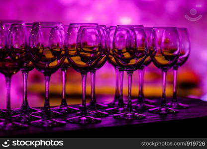 Stemware in purple light. Many glass of wine on a table. Glasses with wine. Filled with half and stand on the holiday table. Furshet. selective focus