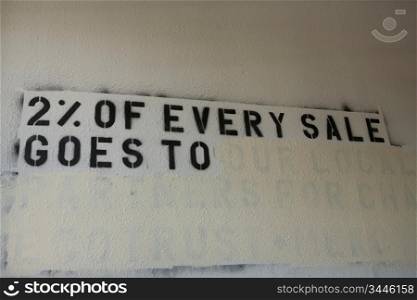 ""Stencil of ""2% of Every Sales Goes To"" on Abandoned Wall""