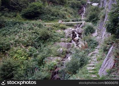 Steps near rock and small river with bridge in Switzerland