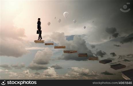 Steps of education. The girl rises upwards on a ladder from books
