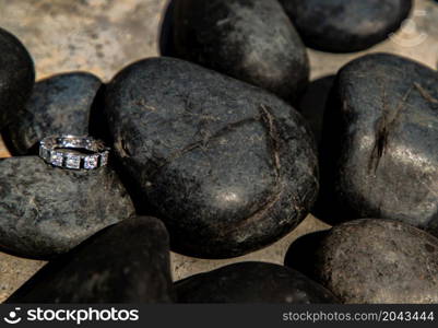 Sterling silver female ring with jewels on stone background. Finger decoration, Accessory, Metal ring, Multi stones. Focus and blur.