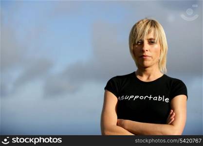 Stern blond woman stood outdoors with arms folded