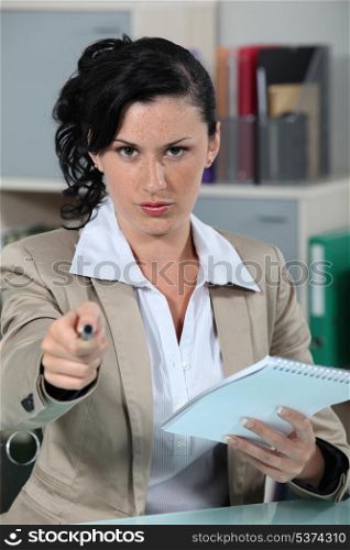 Stern receptionist pointing pen at camera