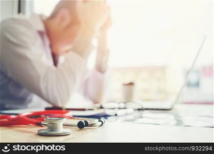Stethoscope and doctor sitting with laptop stress headache about work in hospital