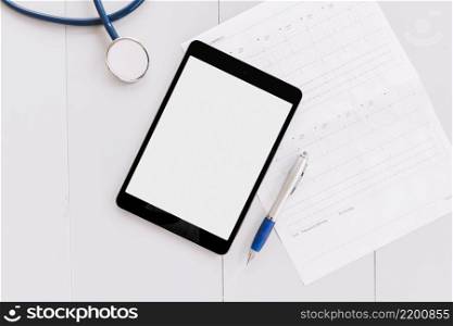 stethoscope digital tablet pen cardiogram chart white wooden surface