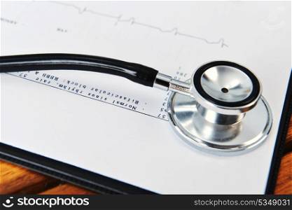 stethoscope on printout of heart monitor -blue tint on wooden background