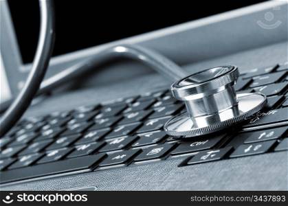 stethoscope on the laptop keyboard, close-up view, blue toned