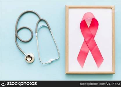 stethoscope pink ribbon white wooden frame colored background