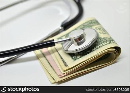 Stethoscope sitting on US dollar bills. Health care costs concept