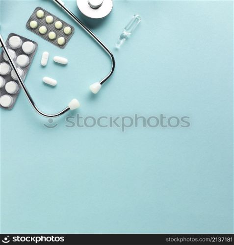 stethoscope with blister packed medicines against blue background