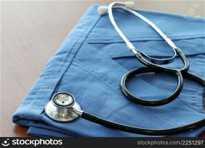 Stethoscope with blue doctor coat on wooden table with shallow DOF evenly matched and background