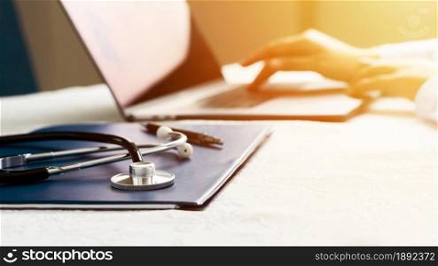 Stethoscope with file and Laptop on desk,Doctor working in hospital writing a prescription, Healthcare and medical concept