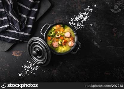 stew with fresh vegetables and sausages on a dark background