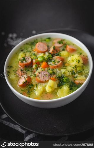 stew with fresh vegetables and sausages on a dark moody background