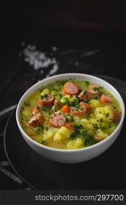 stew with fresh vegetables and sausages on a dark moody background