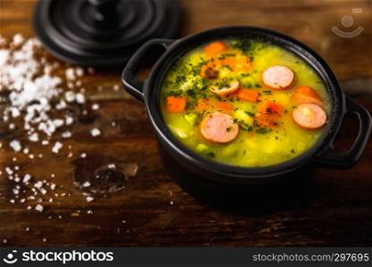 Stew with fresh vegetables and sausages on a wooden background