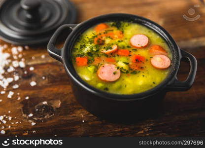 Stew with fresh vegetables and sausages on a wooden background