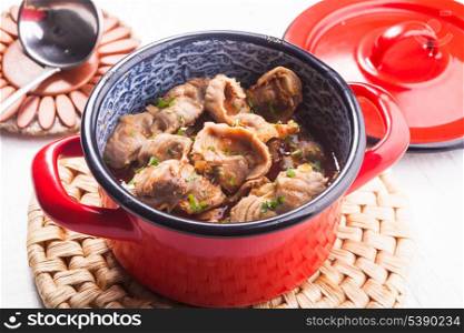 Stewed chicken gizzards in red pan on the mat