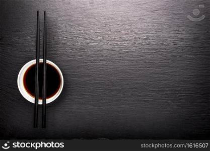 Sticks and soy sauce on a background of black slate. Sticks and soy sauce