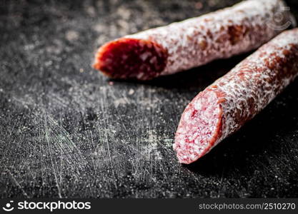 Sticks of salami sausage on the table. On a black background. High quality photo. Sticks of salami sausage on the table.