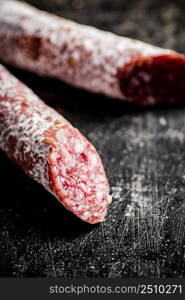 Sticks of salami sausage on the table. On a black background. High quality photo. Sticks of salami sausage on the table.