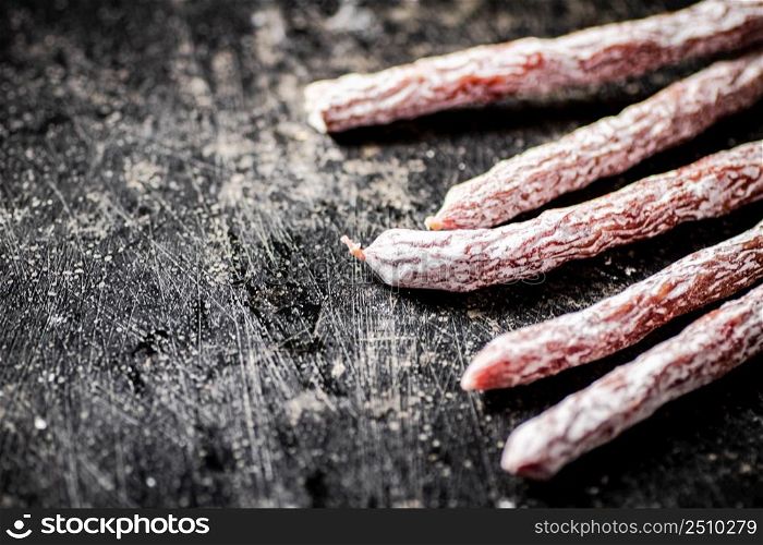Sticks of salami sausage on the table. On a black background. High quality photo. Sticks of salami sausage on the table.