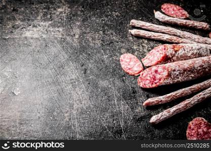 Sticks of salami sausage on the table. On a black background. High quality photo. Sticks of salami sausage on the table.