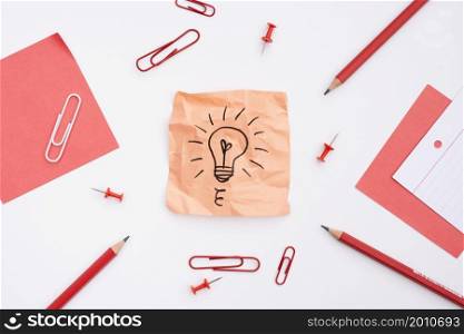 sticky note with drawn light bulb office supplies white background