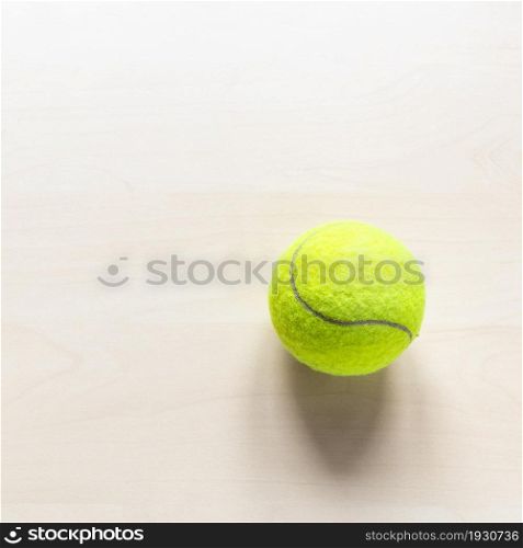 stil life with tennis ball on light brown wooden table with copyspace