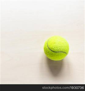 stil life with tennis ball on light brown wooden table with copyspace