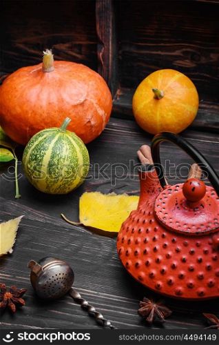 Still life autumn tea party. Warming autumn tea and teapot on background of pumpkin