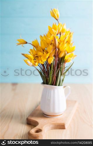 still life - beautiful wild yellow tulips in a vintage vase on a blue background