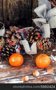 Still life Christmas wreath and tangerines. Woven Christmas wreath decorated with cones on background of ripe tangerines