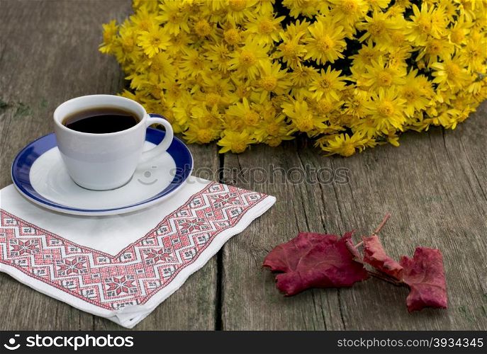 still life, coffee on a napkin, a bouquet of yellow flowers and a red leaf, on a wooden table, fall, a subject drinks