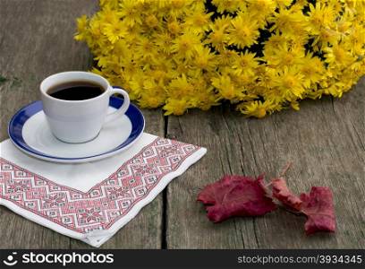 still life, coffee on a napkin, a bouquet of yellow flowers and a red leaf, on a wooden table, fall, a subject drinks
