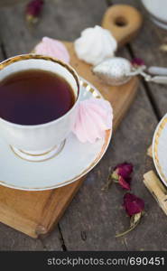 still life - cups of tea, meringues and flowers on a wooden background. atmosphere and mood