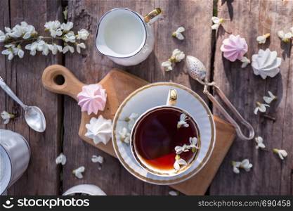still life - cups of tea, meringues and flowers on a wooden background. atmosphere and mood