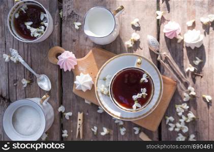still life - cups of tea, meringues and flowers on a wooden background. atmosphere and mood
