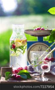 still life - lemonade with lemon, cherry and mint on a vintage wooden chair in the garden. atmosphere and mood