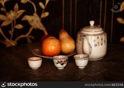 still life low key image of a tea pot cups and fruit