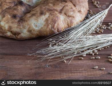 Still life of baked pita bread, wheat ears and scattered grains