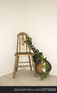 Still life of guitar with garland leaning against a chair.