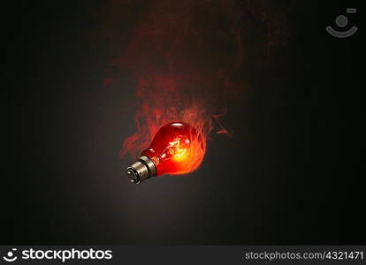 Still life of red smoking illuminated lightbulb