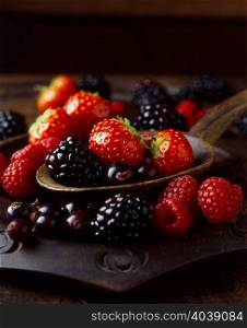 Still life of strawberries, raspberries and blackberries on spoon